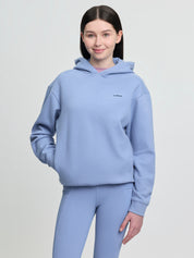 Model wearing LeMieux Young Rider Sia Hoodie in powder blue with hood down and front kangaroo pocket