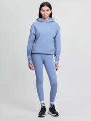 Model wearing LeMieux Young Rider Sia Hoodie in powder blue with matching leggings, striped socks, and black athletic shoes