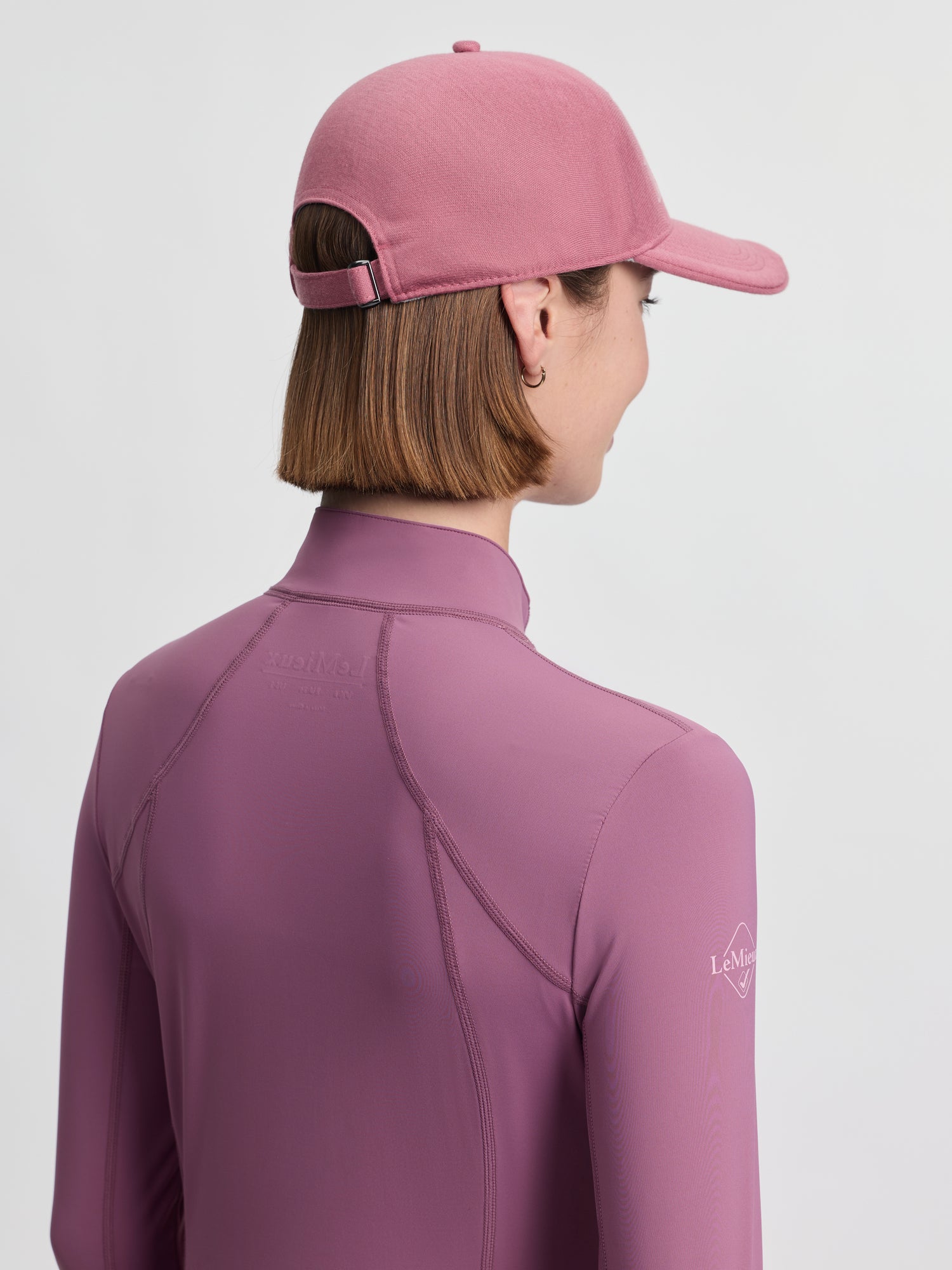 Back view of model wearing LeMieux Lara Cap in Mallow showing adjustable strap and curved brim