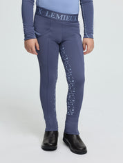 Child wearing LeMieux Mini Pull On Breech in Shadow with elastic logo waistband, side pockets, and silicone grip print on inner legs