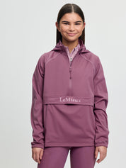 Model wearing LeMieux Young Rider Paige Quarter Zip Waterproof Jacket in Mallow with quarter zip and front pouch pocket