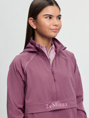 Close-up of model wearing LeMieux Young Rider Paige Quarter Zip Waterproof Jacket in Mallow showing quarter zip and front pouch logo