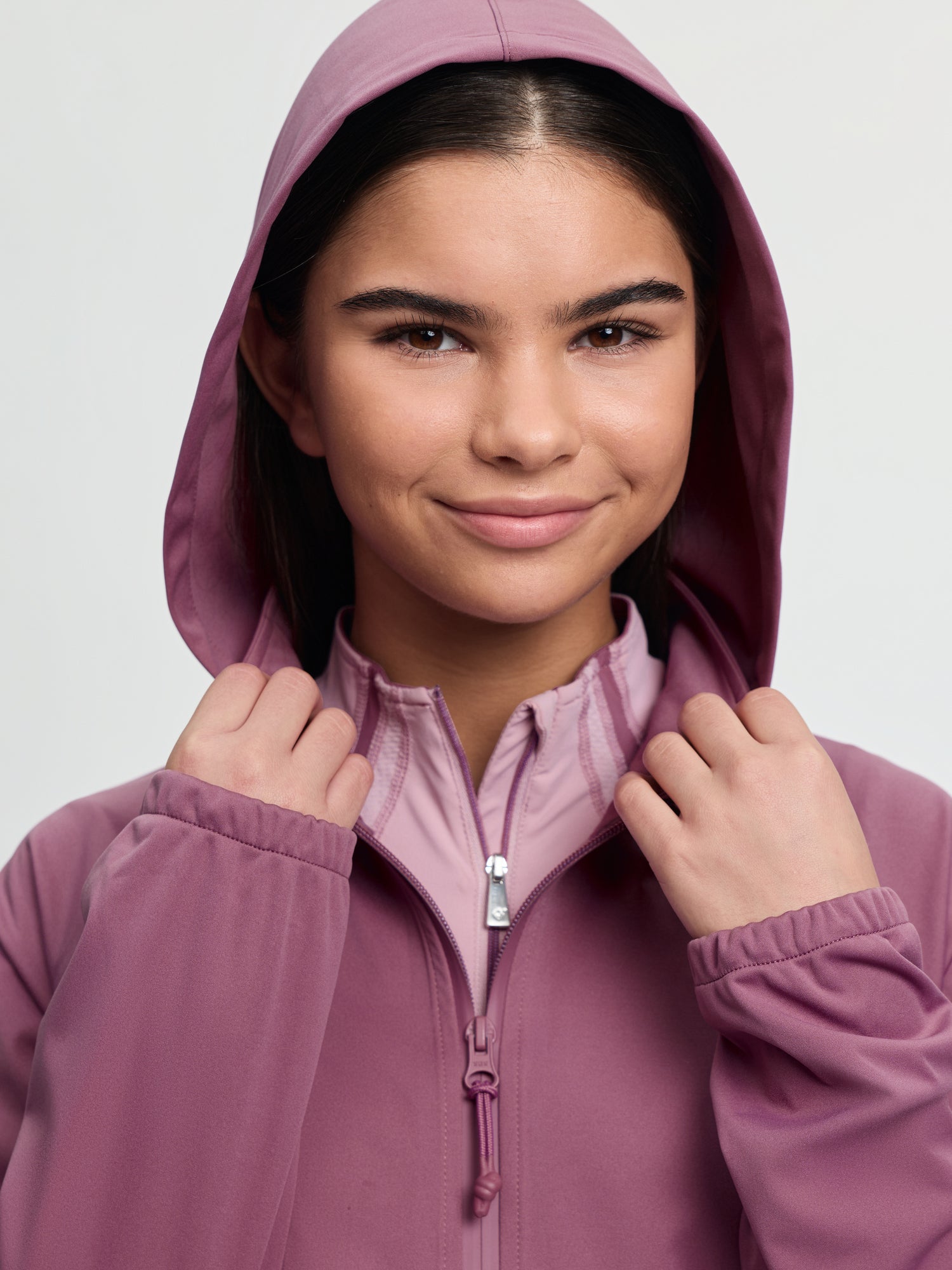 Close-up of model wearing LeMieux Young Rider Paige Quarter Zip Waterproof Jacket in Mallow with hood up