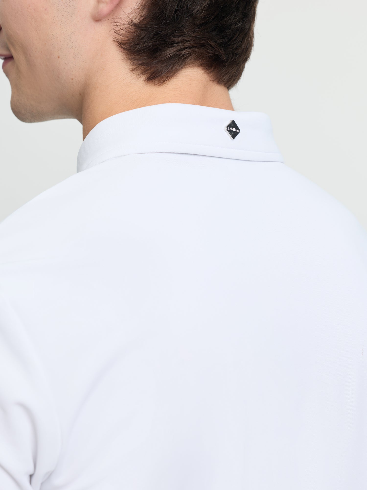 Close-up of back collar on LeMieux men’s short sleeve competition shirt in white showing LeMieux logo tab