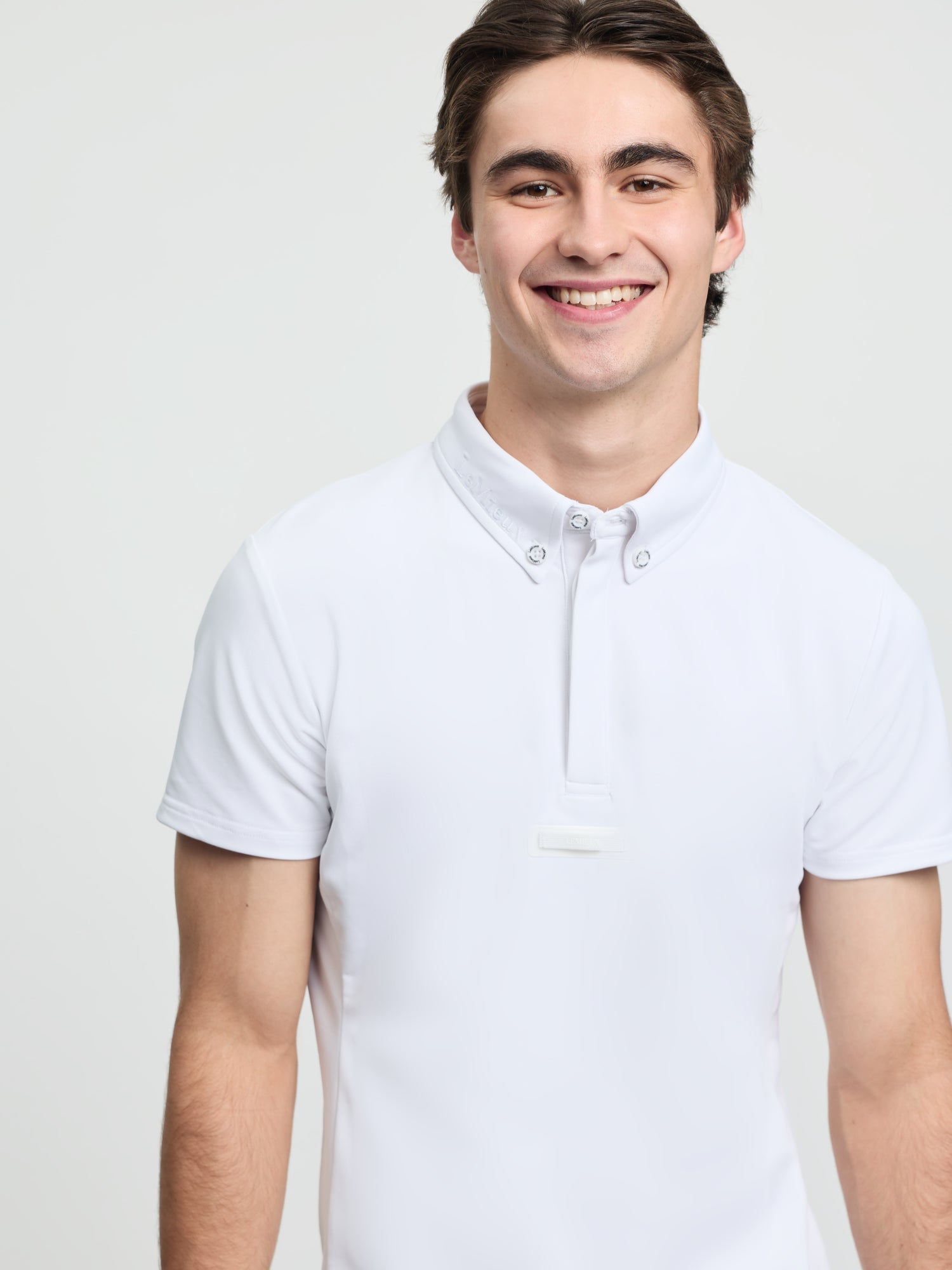 Close-up of model wearing LeMieux men’s short sleeve competition shirt in white with button collar and quarter placket