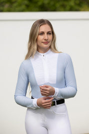 Model wearing LeMieux Arielle Long Sleeve Show Shirt in Mist with white stand collar, pleated bib front, and white cuffs