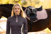 Front view of a female model wearing the Cocoa LeMieux Matilda Mid Layer while standing in front of a horse outside