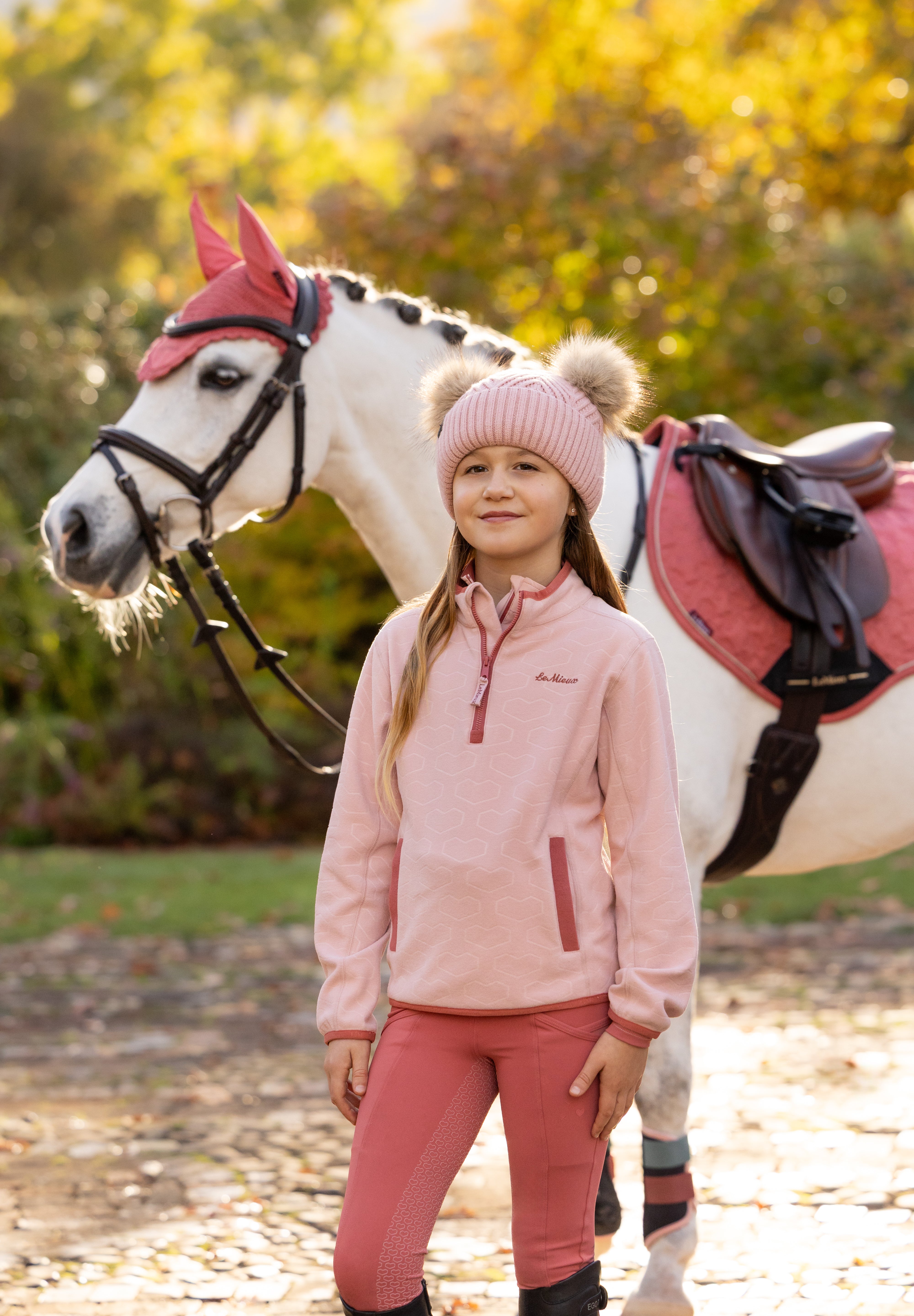 Front view of a young female model wearing Petal LeMieux Mini Maggie Heart Fleece and standing outdoors