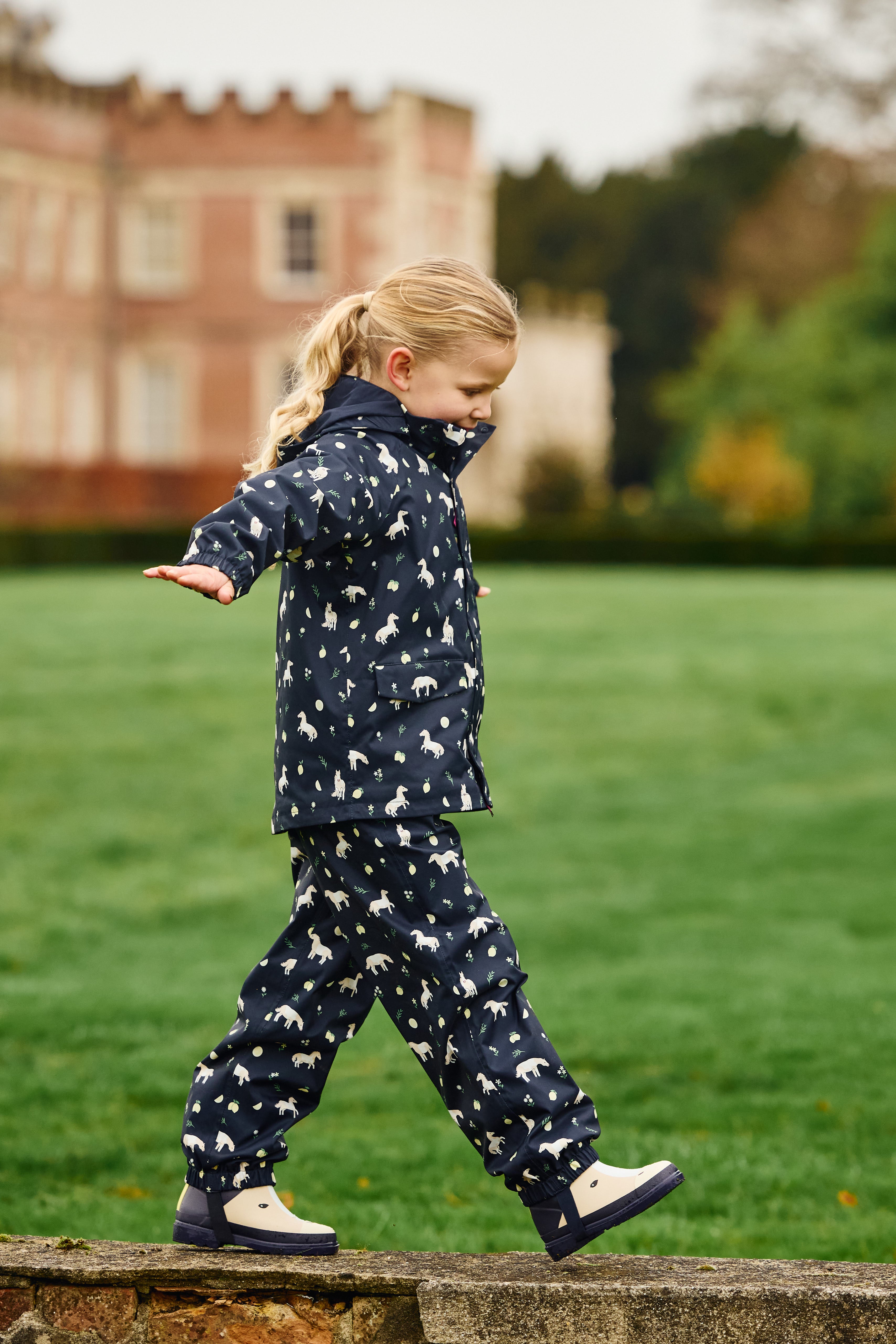 Front view of a young female model wearing Navy LeMieux Mini Pippin Splash Jacket and walking outdoors