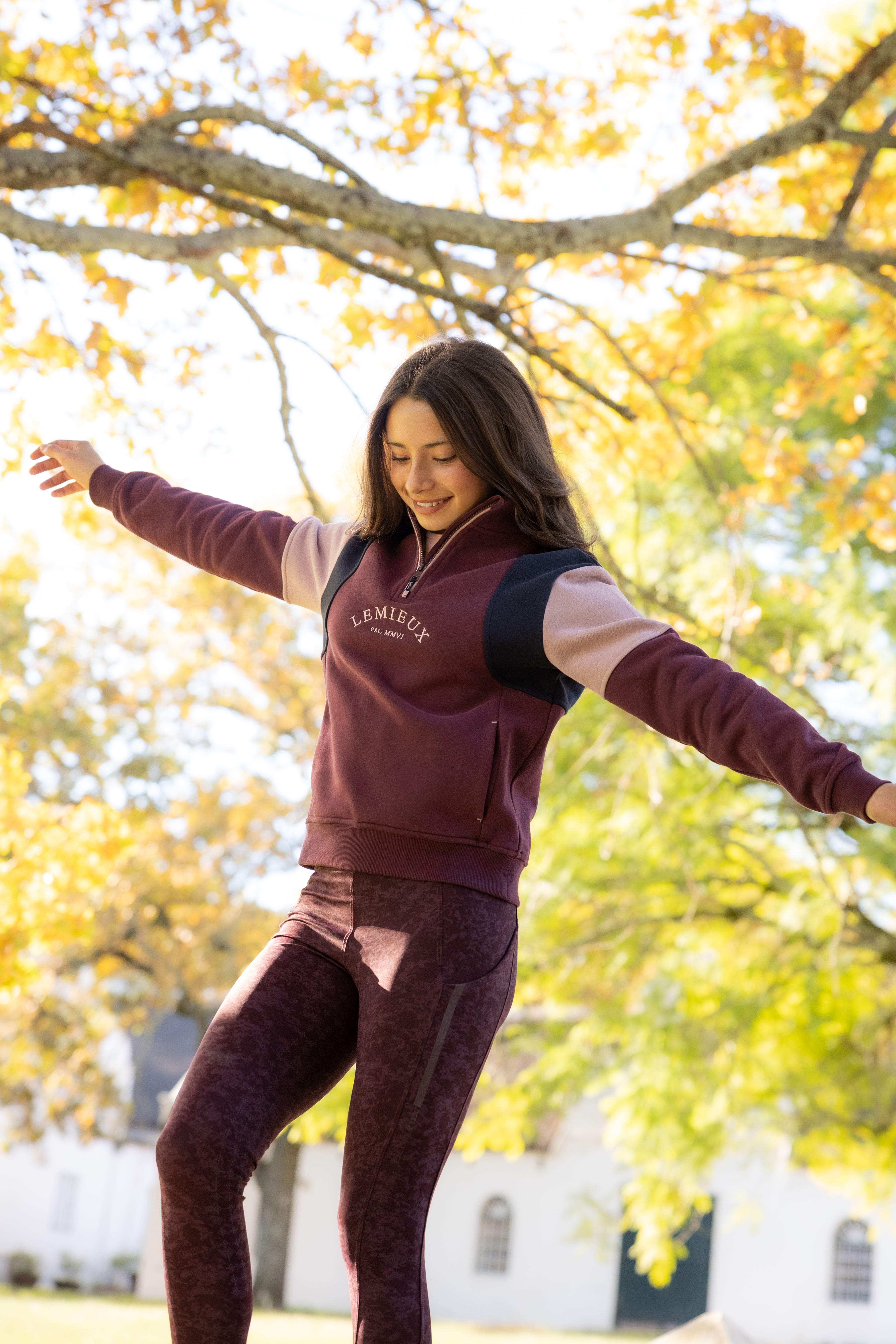 Angled front view of a young female model wearing Bramble LeMieux Young Rider Viola Quarter Zip Sweatshirt outdoors