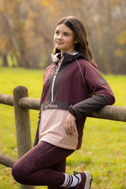 Angled front view of a young female model wearing Bramble LeMieux Young Rider Bailey Waterproof Anorak outdoors