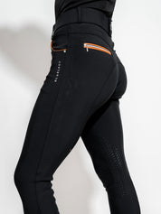 Side view of a model wearing the black/cognac KL Select Gabrielle Knee Patch Breech on a plain background