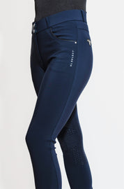 Angled side view of a model wearing the navy KL Select Gabrielle Knee Patch Breech on a plain background