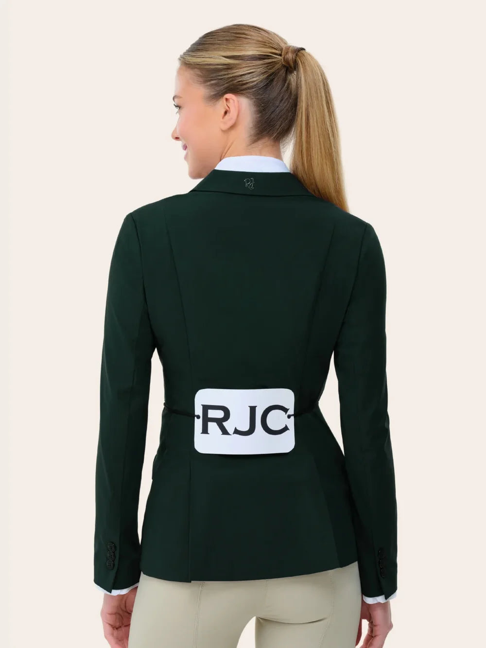 Back view of a female model wearing the green RJ Classics Legacy Lite Show Coat with RJC competition number tabard on a plain background