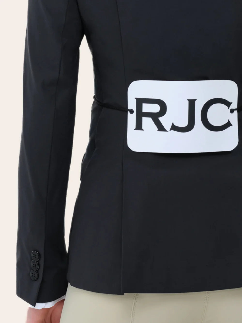 Close-up back view of a young female model wearing the black RJ Classics Legacy Lite Jr Show Coat with RJC competition number tavard on a plain background