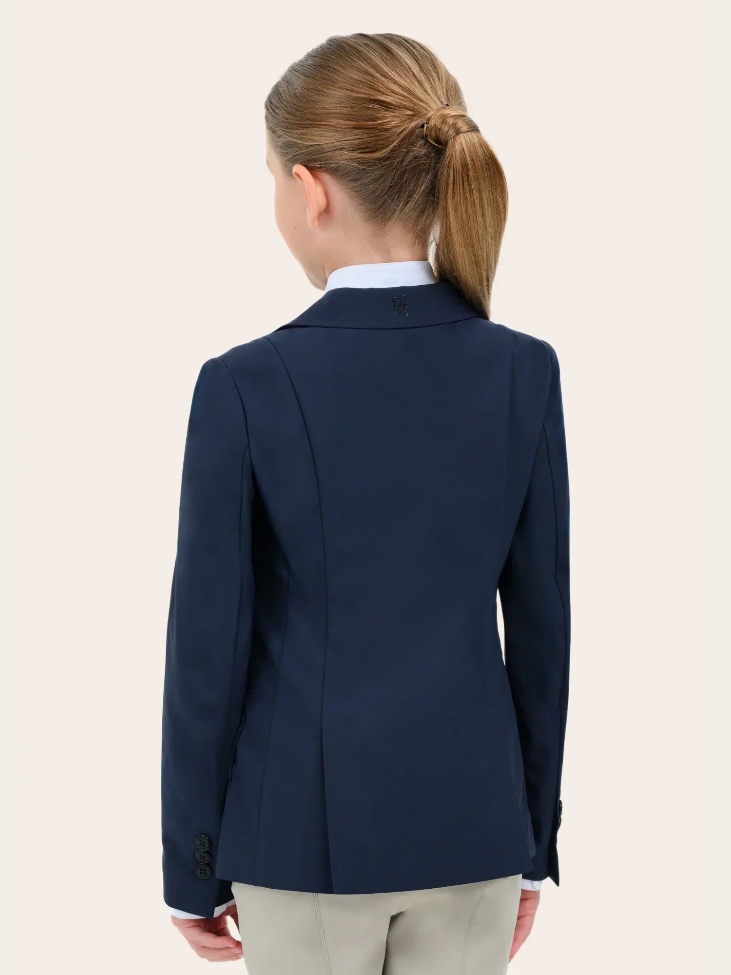 Back view of a young female model wearing the navy RJ Classics Legacy Lite Jr Show Coat on a plain background