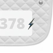 Side view of a white pad with numbers 378 and a Lightning Bolt Dubois Cheval Number Pin Charm on a white background