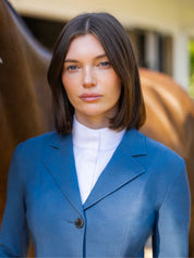 Close-up front view of a model wearing the blue weave RJ Classics Monterey Show Coat with a horse in the background