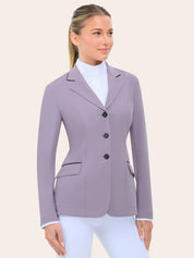 Front view of the RJ Classics Monterey Show Coat Eleganza Edition in Dusty Lilac, a fitted equestrian show jacket with black collar piping, three-button front closure, and flap pockets with contrast piping, shown over a white high-collar show shirt and white riding breeches against a plain light background.