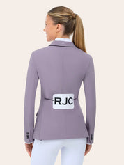 Back view of the RJ Classics Monterey Show Coat Eleganza Edition in Dusty Lilac, a fitted equestrian show jacket with black collar piping, center back seam, and buttoned cuffs, shown over a white show shirt and white riding breeches on a model against a plain light background.