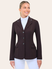 Angled front view of the RJ Classics Monterey Show Coat in fig, a fitted equestrian show jacket with notched lapel and contrast piping, three-button front closure, and flap pockets, shown over a white high-collar show shirt and white riding breeches against a plain light background.