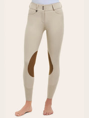 Angled front view of the RJ Classics Olivia Luxe-Tek Breech in Sand, showing the double-button waistband with belt loops, smooth stretch fabric, brown suede knee patches, and perforated lower-leg panels, photographed on a model against a plain light background.