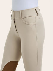 Close-up of the RJ Classics Olivia Luxe-Tek Breech in Sand showing the wide waistband with belt loops, zip front closure, front pocket, and RJ logo embroidery above the brown suede knee patch.