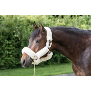 Angled side view of a horse standing outside wearing the Perri's Natural Sheepskin Shipping Halter