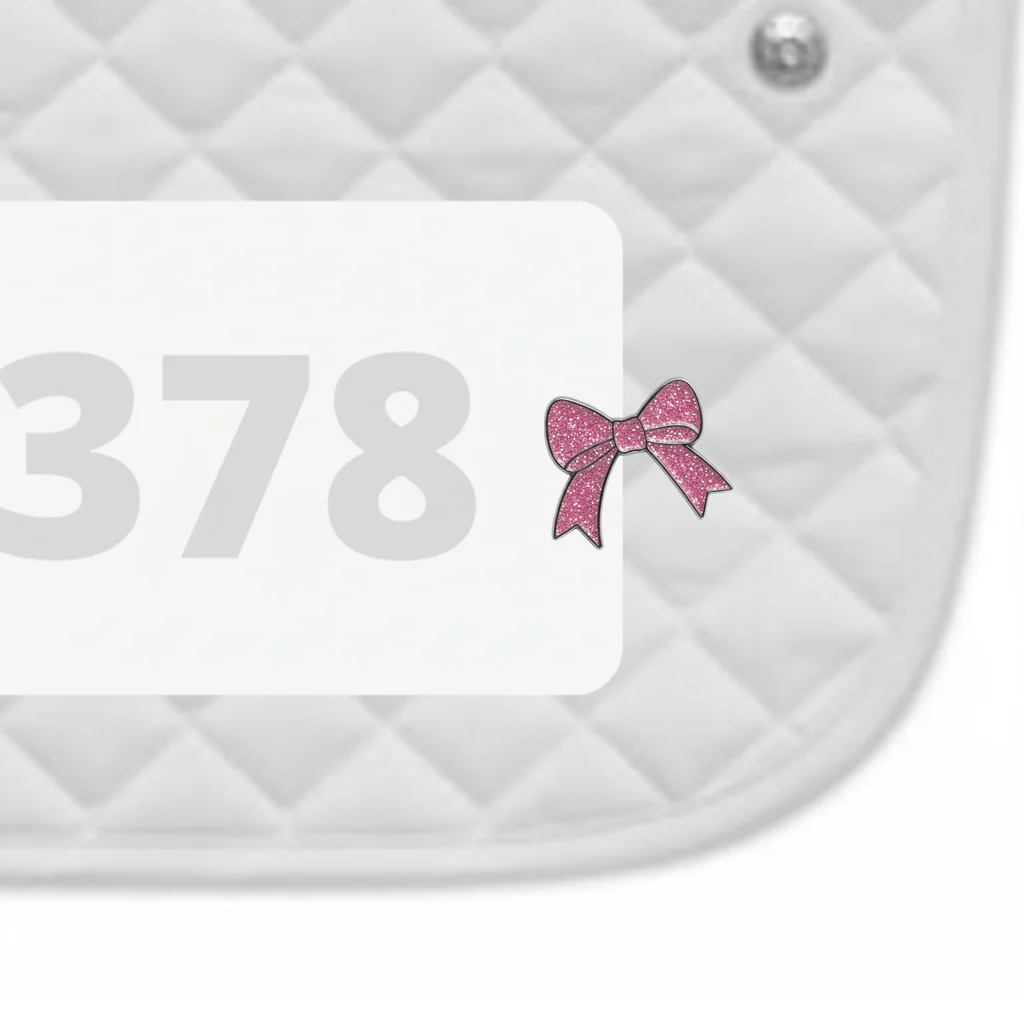 Side view of a white pad with numbers 378 and a Pink Bow Dubois Cheval Number Pin Charm on a white background