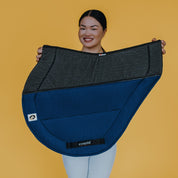 Side view of a model holding the navy Ecogold Secure Cross Country Pad on a yellow background