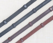 Side by side views of black and brown pairs of the KL Select Soft Grip Reins with Stops on a textured background
