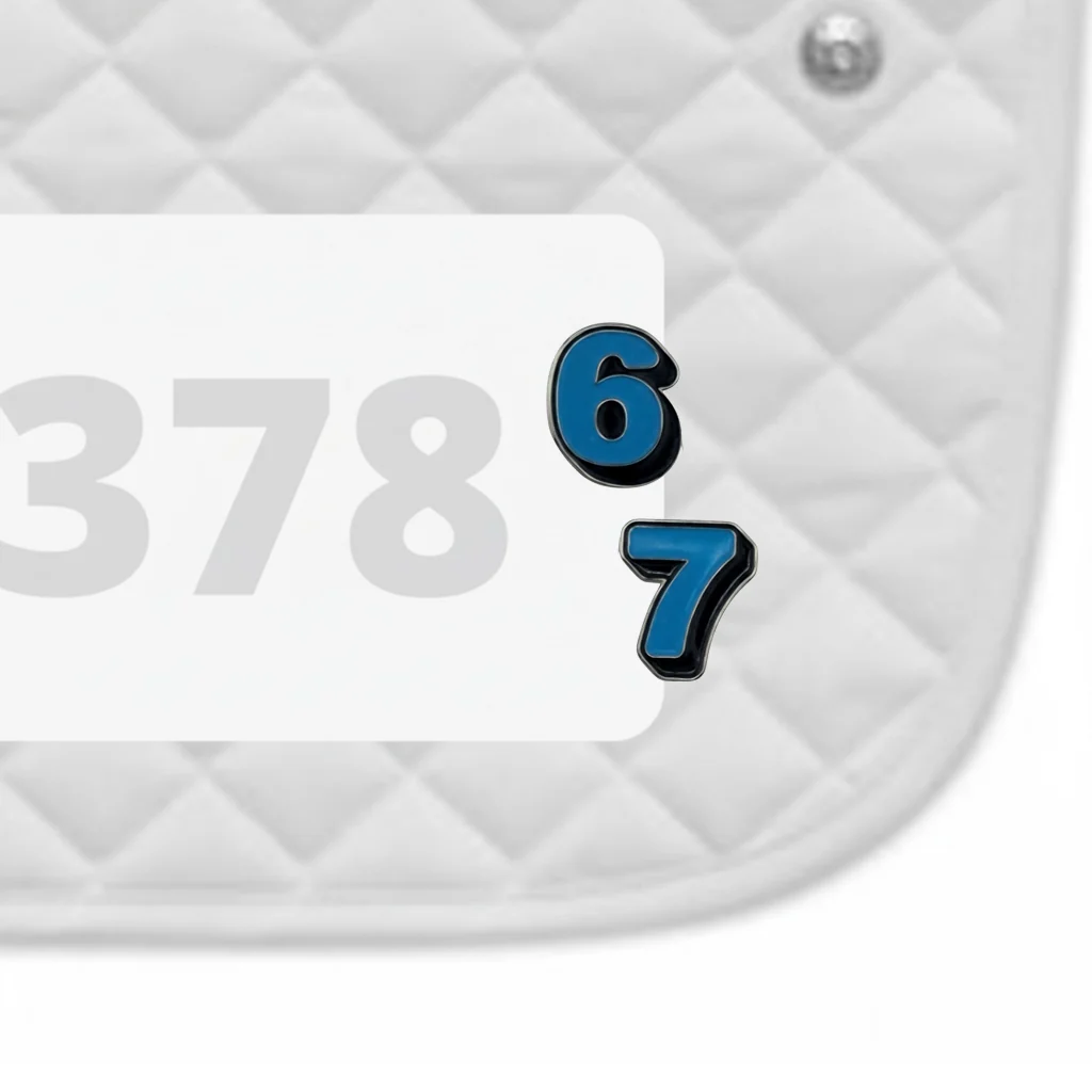 Side view of a white pad with numbers 378 and a pair of Six Seven Dubois Cheval Number Pin Charms on a white background