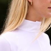 Close-up angled front view of a female model wearing the white TKEQ Sloan Competition Long Sleeve Top