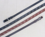 Side-by-side views of  black and brown pairs of Red Barn 5/8" Thumb Grip Reins on a patterned background