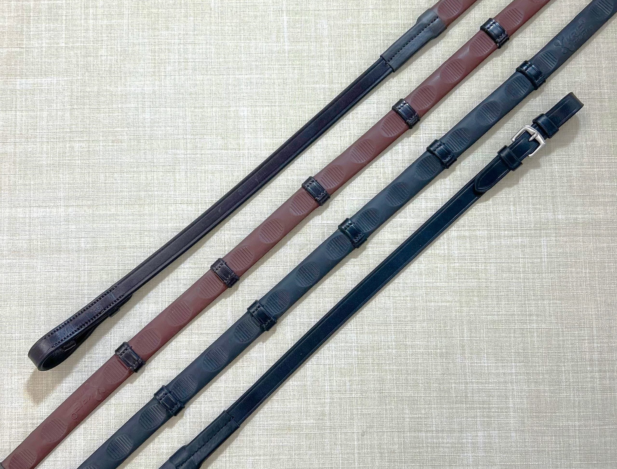 Side-by-side views of both the brown pin and black buckle Red Barn 5/8" Thumb Grip Reins with Stops on a textured background