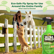 Woman sitting on white fence next to horse and dog with a bottle of Ultrashield Green in the foreground