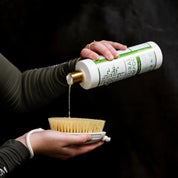 Model pouring Hairy Pony Natural Shampoo from a bottle onto a brush.