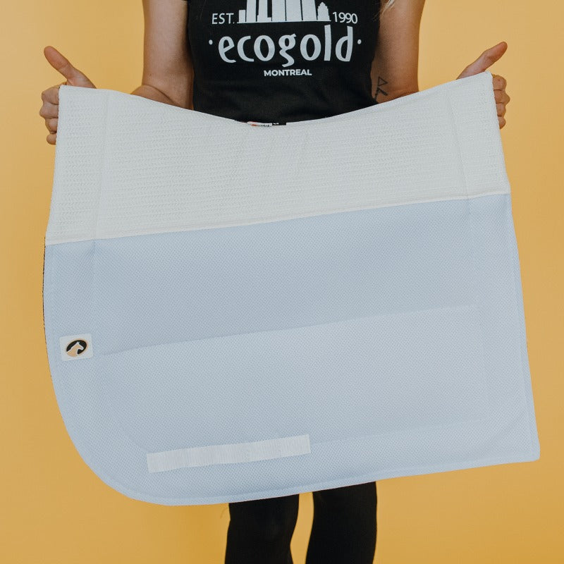 View of a model holding the white Ecogold Secure Dressage Pad on a yellow background