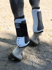 Angled back view of a gray horse wearing the white Majyk Equipe Vented Infinity Open Front Tendon Jump Boot while standing in the dirt outside