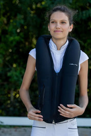 Model wearing the Helite Zip'In 2 Airbag in black with the airbags inflated, standing outside