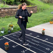 View of a model walking on the All Designs Equine Dressage Arena Practice Your Test Outdoor Horse Trainer Rug on an outdoor patio