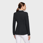 Back view of a female model wearing the black Samshield Alix Show Coat on a plain background
