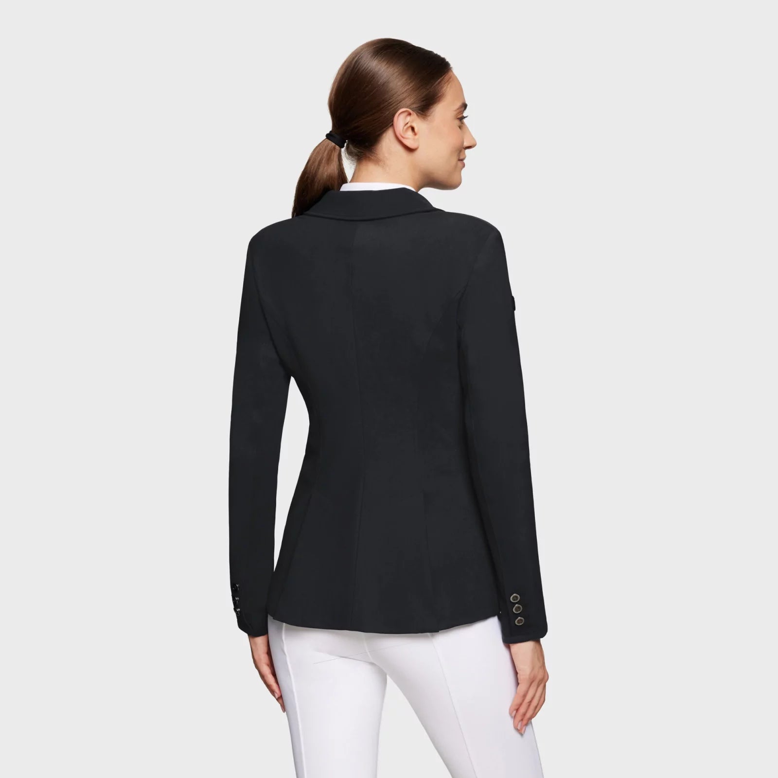 Back view of a female model wearing the black Samshield Alix Show Coat on a plain background