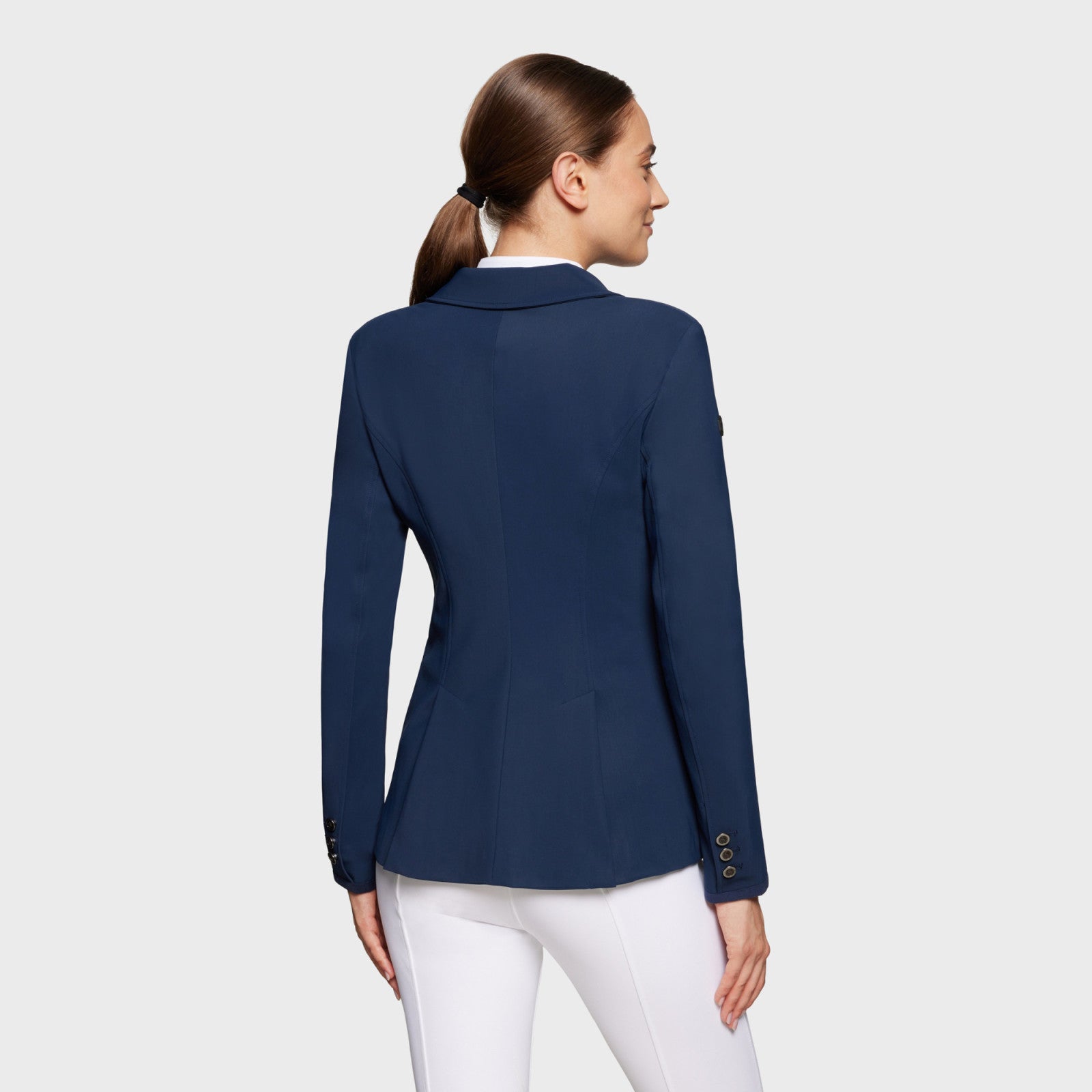 Back view of a model wearing the navy blue Samshield Alix Show Coat on a plain background