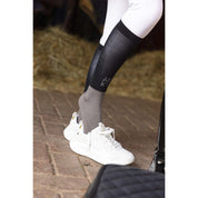 Side view of a model wearing the black ANKY Competition Socks with white tennus shoes white standing in a barn