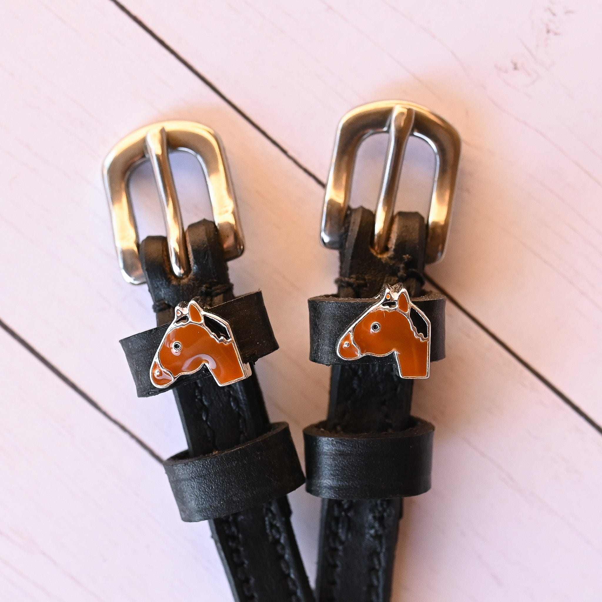 Close-up view of the Bay Horse Mane Jane Spur Straps on a white wood plank background
