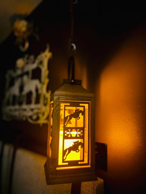 Side view of the lit jumping All Designs Equine Horse Lantern hanging on a brown wall