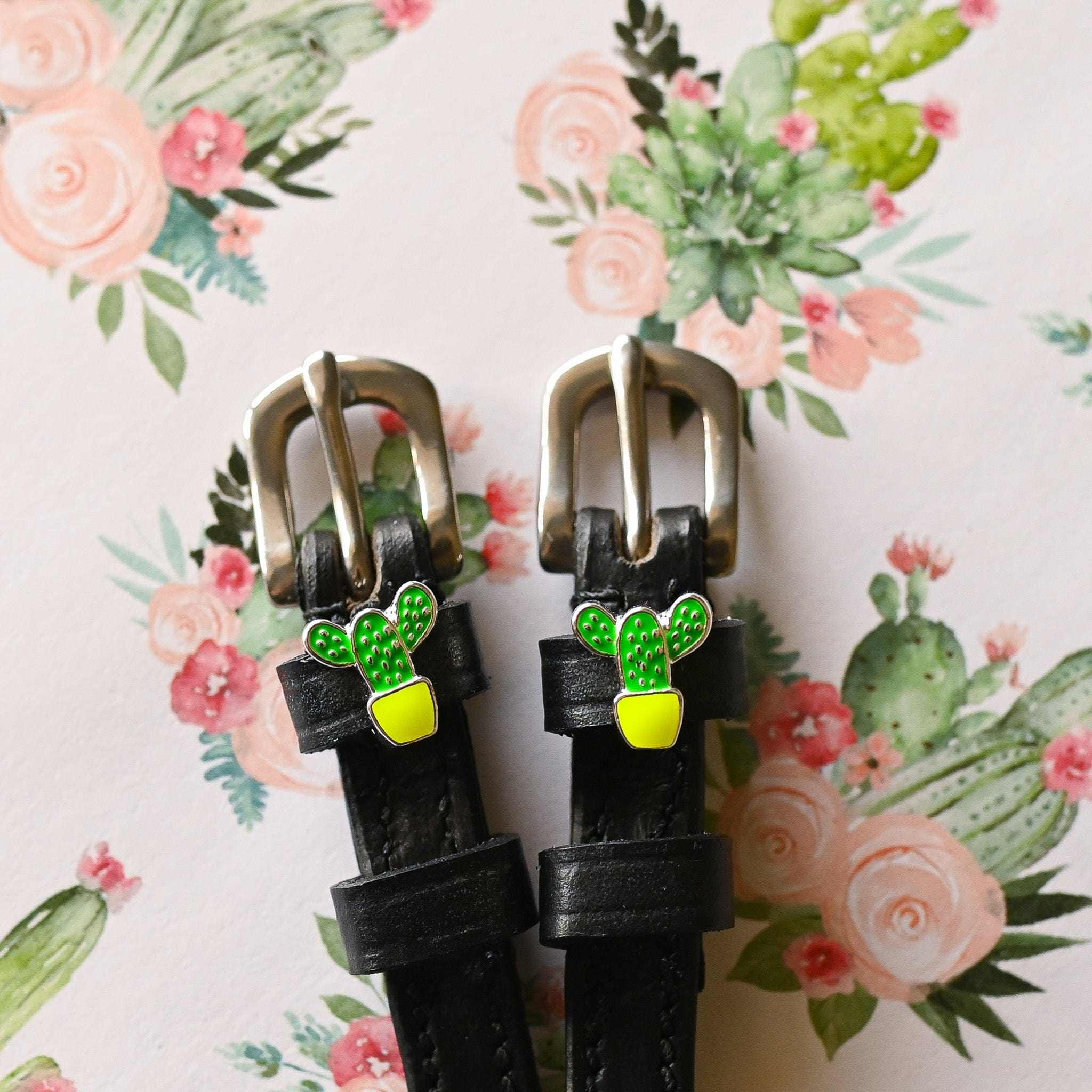 Close-up view of the Cactus Mane Jane Spur Straps on a pink floral cactus background
