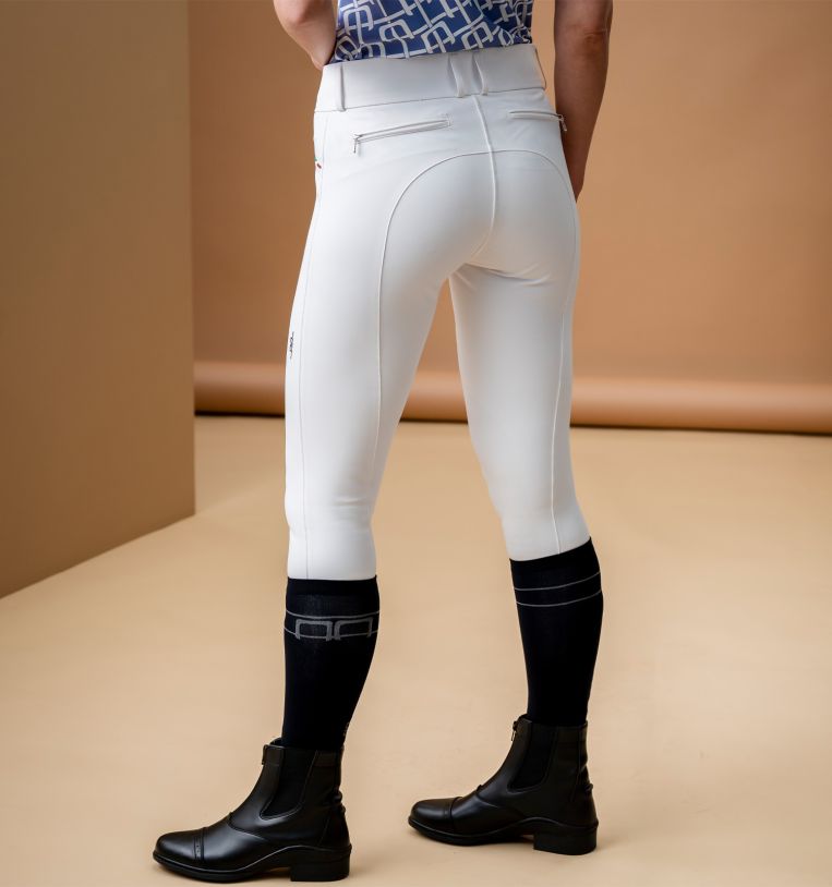 Model wearing Horseware Alessandro Albanese Aria Full Seat Mid Rise Breech in core white with black riding boots, back view