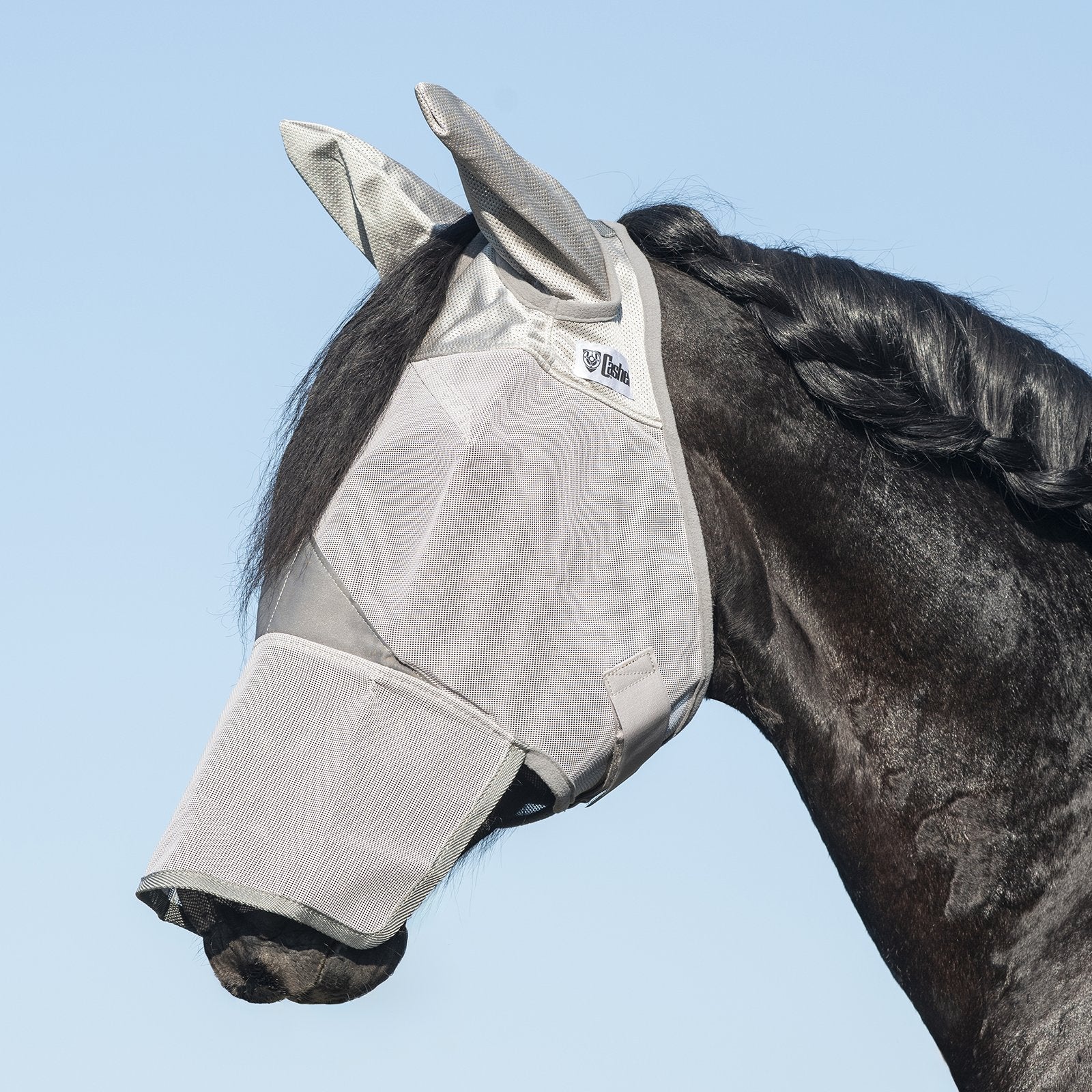 Side view of a black horse wearing the gray warmblood Cashel Crusader Fly Mask with Long Nose and Ears against a blue sky background